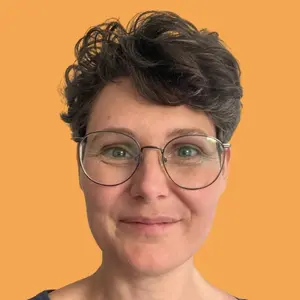 Stefanie Hahne – Soul- & Self-Leadership Erfahrungen Porträt des lächelnden Gesichts von Facereading-Expertin Stefanie Hahne vor einem orangefarbenen Hintergrund, die ihre Soul- & Self-Leadership Erfahrungen nach einem erfolgreichen Mentoring teilt.